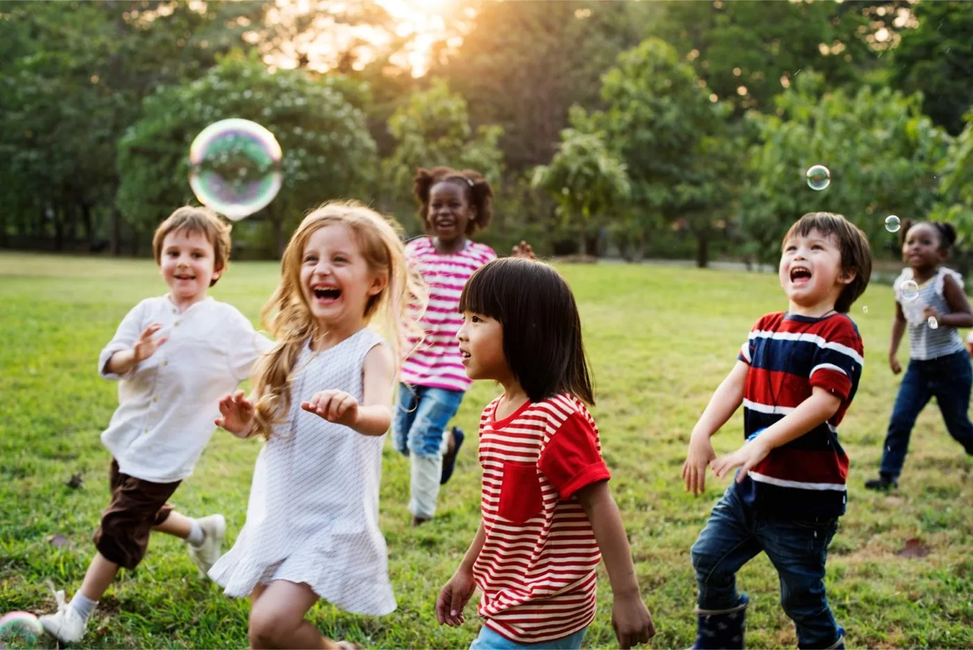 Children playing together outdoors and chasing bubbles